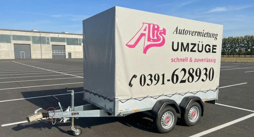 Miet-Anhänger mit Plane von Alis Autovermietung auf Parkplatz stehend